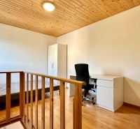 Helles Zimmer in einer 2-Zimmer-Wohnung mit Holzelementen und Schreibtisch.