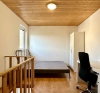 Schlafzimmer in einer 2-Zimmer-Wohnung mit Holzboden, Holzdecke und Möbeln.