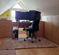 Dachbodenkontor in einer 2-Zimmer-Wohnung mit Holzboden und Schreibtisch.