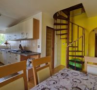 Küche in einer 2-Zimmer-Wohnung mit Wendeltreppe und hellen Schränken.
