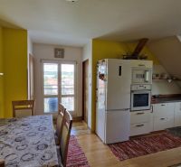 Küche in einer 2-Zimmer-Wohnung mit Holzelementen und gelber Wand.