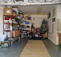 Eine Garage voller gelagerter Gegenstände und Regalsysteme, neben einem Waschbecken und einer Leiter.