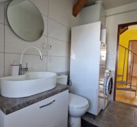 Badezimmer in einer 2-Zimmer-Wohnung mit Waschbecken, rundem Spiegel und Waschmaschine.