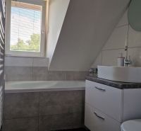 Badezimmer in einer 2-Zimmer-Wohnung mit Badewanne, Waschbecken und sechseckigen Fliesen.