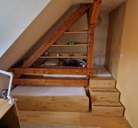 Podkrovná miestnosť s drevenými prvkami, posteľou a pracovným stolom v 2-izbovom byte.

Dachgeschosszimmer mit Holzelementen, Bett und Schreibtisch in einer 2-Zimmer-Wohnung.