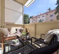 Balkon einer 2-Zimmer-Wohnung mit gemütlicher Sitzecke und Grünpflanzen.