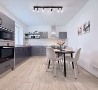 Moderne Küche in einer 2-Zimmer-Wohnung mit Holzboden und Esstisch.