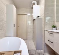 Badezimmer in einer 2-Zimmer-Wohnung mit Badewanne, Möbeln und Fliesen mit geometrischen Mustern dekoriert.