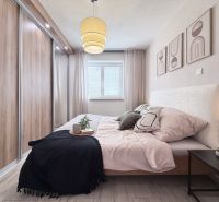 Schlafzimmer in einer 2-Zimmer-Wohnung mit Holzboden, großem Einbauschrank und Wanddekorationen.