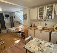 Küchenecke mit Schränken, Tisch und Sofa, Boden mit Holzdekor in einem Einfamilienhaus.