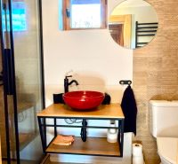 Badezimmer in einem Einfamilienhaus, mit Holzboden, Fenster und Spiegel.