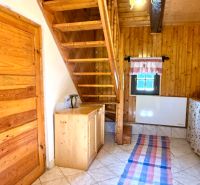 Innenraum eines Einfamilienhauses mit Holztreppe, -decke und -türen, Fliesen auf dem Boden.