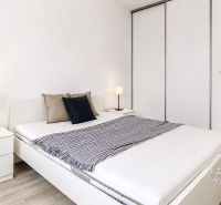 Schlafzimmer mit Bett und Schrank in einer 2-Zimmer-Wohnung, Boden mit Holzdekor.