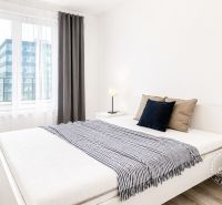 Schlafzimmer mit Holzboden und großem Fenster in einer 2-Zimmer-Wohnung.