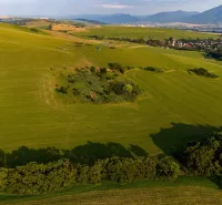Weitläufige grüne Felder und Hügel in Liptovský Trnovec, die einen Blick auf ungewöhnliche Immobilien bieten.