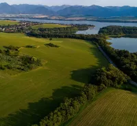 Liptovský Trnovec bietet weitläufige Grünflächen mit einem See, umgeben von Waldgebieten und Feldern.