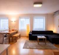 Wohnzimmer einer 4-Zimmer-Wohnung mit Sofa, Esstisch und Holzboden.