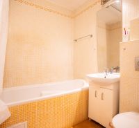 Badezimmer in einer 4-Zimmer-Wohnung mit Badewanne, Waschbecken und Toilette, helle Fliesen.