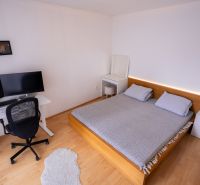 Schlafzimmer mit Bett, Schreibtisch und Boden mit Holzdekor in einer 4-Zimmer-Wohnung.