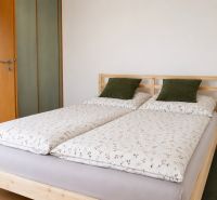 Schlafzimmer mit Doppelbett, Kissen in einer 2-Zimmer-Wohnung auf einem Boden mit Holzdekor.