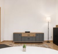 Wohnzimmer mit Holzboden, Möbeln und Stehlampe in einer Zweizimmerwohnung.