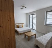 Ein Zimmer mit einem Bett, einem Tisch und einem Boden mit Holzdekor in einer Einzimmerwohnung.