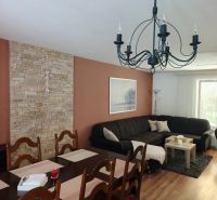 Wohnzimmer in einem Einfamilienhaus mit Sofa, Esstisch und Holzboden.