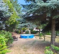 Ein Garten in Mankovce mit einem Pool und einer Bank im Schatten der Bäume neben einem Einfamilienhaus.