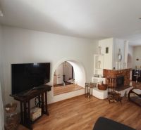 Wohnzimmer mit Kamin in einem Einfamilienhaus, Boden mit Holzdekor, Fernseher auf einem Tisch.