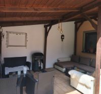Überdachte Terrasse eines Einfamilienhauses in Mankovce mit Rattanmöbeln und Kamin.