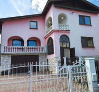 Ein Einfamilienhaus in Mankovce mit rosa Fassade, einem Obergeschoss und einem schmiedeeisernen Zaun.