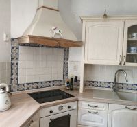 Weiße Küche mit Kochfeld, Dunstabzugshaube und Boden in Holzoptik in einem Einfamilienhaus.