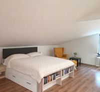 Schlafzimmer in einem Einfamilienhaus mit Holzboden, Bett und Sessel.