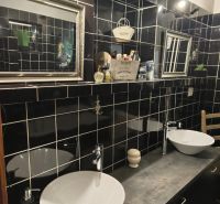 Badezimmer in einem Einfamilienhaus mit schwarzen Fliesen, zwei Waschbecken und Spiegeln.
