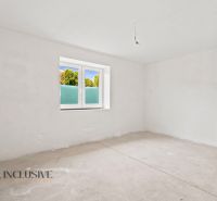 Ein leerer Raum in einem Einfamilienhaus ohne Bodenbelag und mit weißen Wänden.