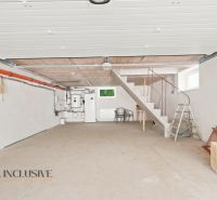Garage in einem Einfamilienhaus mit Betonboden und Treppen, einfache weiße Wände.