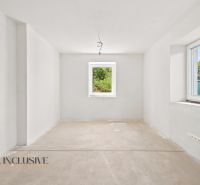 Ein leerer Raum in einem Einfamilienhaus mit weißen Wänden und einem großen Fenster.