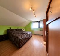 Dachzimmer mit Bett, Schrank und Holzboden in einem Einfamilienhaus.