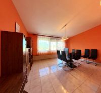 Wohnzimmer in einem Einfamilienhaus mit orangefarbenen Wänden und schwarzen Stühlen.