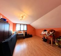 Dachzimmer mit Schreibtisch, Sofa und Holzboden.