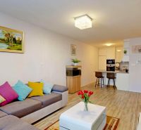 Wohnzimmer einer 3-Zimmer-Wohnung mit Holzboden und bunten Kissen.