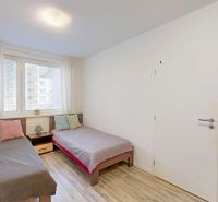 Zwei Betten mit bunten Kissen und ein Boden mit Holzdekor in einer 3-Zimmer-Wohnung.