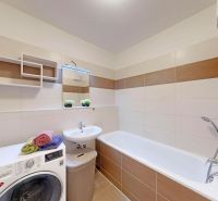 Badezimmer in einer 3-Zimmer-Wohnung mit Badewanne, Waschmaschine und modernem Fliesenbelag.
