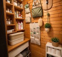 Gemütliche Kammer in der Blockhütte mit praktischen Regalen, einem Organizer und dekorativen Pflanzen.