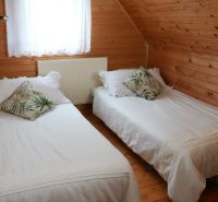 Ein Schlafzimmer in einer Hütte mit Holzverkleidung, zwei Betten und dekorativen Kissen.