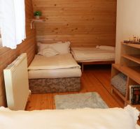 Holzverkleidung im Zimmer einer Hütte, zwei Betten, Boden mit Holzdekor, Bücherregal.