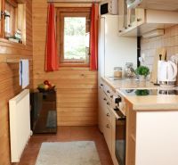 Eine Küche in einer Hütte mit Holzdekor, weißen Geräten und einem Fenster mit Ausblick.
