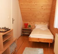 Einzelzimmer mit Holzboden, einem Schachbrett auf dem Tisch und einem Fenster mit weißem Vorhang.