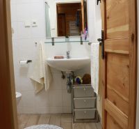 Ein Badezimmer in der Hütte mit Waschbecken, Spiegel und Boden mit Holzdekor.