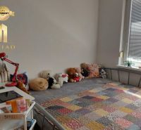 Ein Zimmer in einer Einzimmerwohnung mit einem Bett, einer bunten Decke und Plüschtieren.